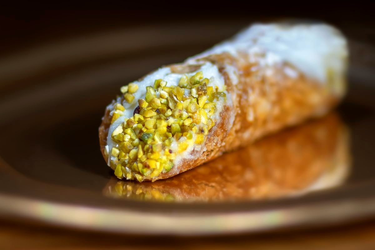 A cannoli dusted with icing sugar on a plate