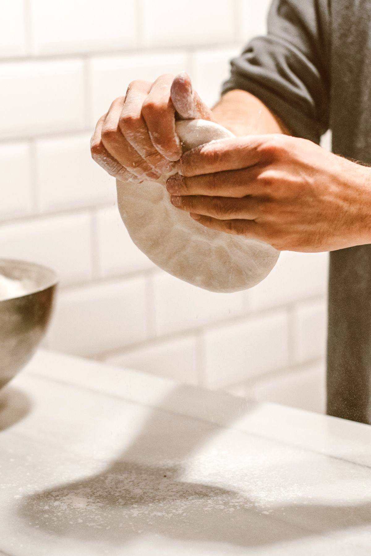 Hands dusted in flour shaping dough on a bakery counter